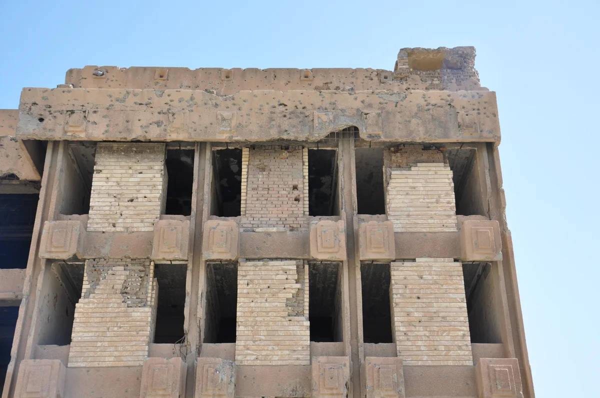 Close-up of bullet and shrapnel damage on the building's concrete facade, a relic of the 1991 battle
