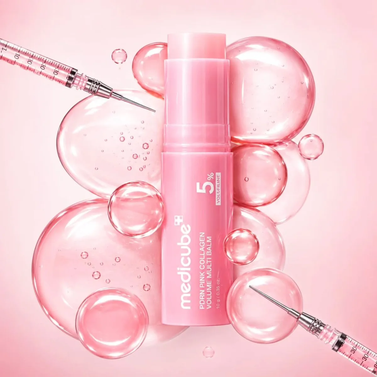 بالم استیک صورتی مدیکیوب PDRN Pink Collagen Volume Multi Balm ۱۰ گرم روی پس زمینهٔ حباب های صورتی